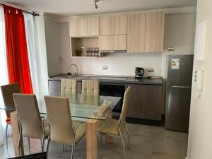 Una cocina con mesa y sillas y un refrigerador. en Departamento Alto Serena V, en La Serena
