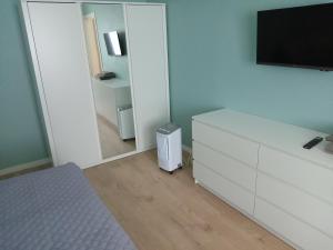 a bedroom with a white dresser with a tv and a mirror at Apartment by the bar in Imatra