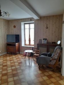 a living room with a couch and a tv at Maison proche le PAL 4kms in Thiel-sur-Acolin