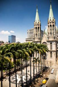 a cathedral with palm trees in front of a building at Estação Sé Hotel in Sao Paulo