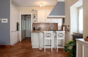 a kitchen with white cabinets and a island with bar stools at Casa Parco degli Ulivi in Frascati