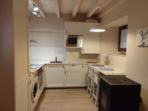 a small kitchen with white cabinets and a microwave at La casina de Tielve de Cabrales dentro del Parque Nacional Picos de Europa in Tielve