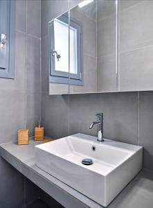 een badkamer met een witte wastafel en een spiegel bij Paros Iconic Apartments in Kampos Paros