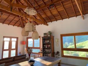 a living room with a wooden table and windows at Casa Mescla in São Bento do Sapucaí
