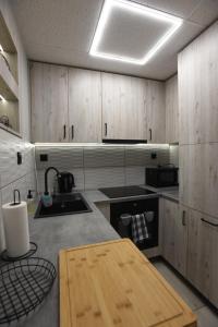 a kitchen with wooden cabinets and a wooden table at Apartament na Tylnej w Śremie - Nr 1 Parter in Śrem