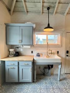a kitchen with a sink and blue cabinets and a window at Whitewater Cottage- IN TOWN walk to everything in Lava Hot Springs