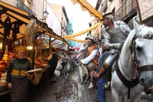 eine Gruppe von Menschen reitet auf Pferden durch einen Markt in der Unterkunft Hotel Complutense in Alcalá de Henares