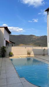 a swimming pool in front of a house at Ap 3 Ouro Pret com piscina aquecimento solar e churrasqueira in Ouro Preto