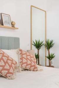 a bed with brown and white pillows on it at Maré Baixa Oceanside Apartment in Nazaré