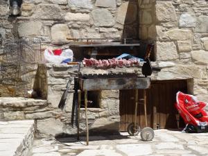 a stone building with a grill with meat on it at Blue Cottage in Apsiou