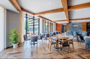 a dining room with tables and chairs and windows at Hotel Archi Kokhta Bakuriani Apartment 305 in Bakuriani