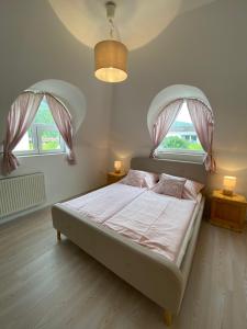 a bedroom with a large bed with two windows at Vázsonyi Vendégház in Balatonfüred +67 photos