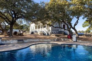 a swimming pool in front of a house with trees at Unique Victorian Estate Pets Welcome Pool BBQ Picnic Privacy in Dripping Springs
