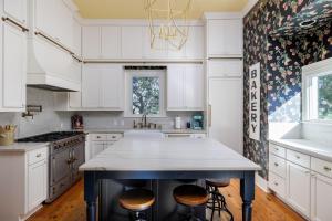 a kitchen with white cabinets and a island with stools at Unique Victorian Home*Pool*Pets*Firepit in Dripping Springs