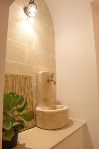 ein Badezimmer mit einem steinernen WC auf einer Theke mit einer Pflanze in der Unterkunft Suite San Francesco in Grottaglie