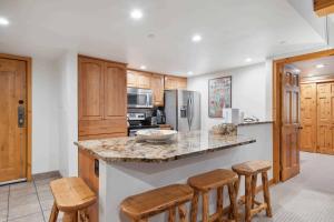 a kitchen with wooden cabinets and a island with bar stools at Lodge at Lionshead 110-100 in Vail +31 photos