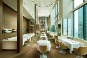 a restaurant with white tables and chairs and large windows at Conrad Tokyo in Tokyo