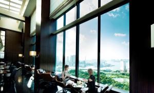 two people sitting in chairs in a room with large windows at Conrad Tokyo in Tokyo
