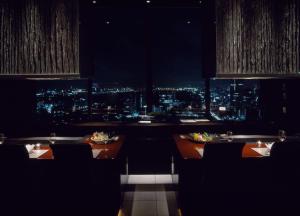 a restaurant with a view of a city at night at Conrad Tokyo in Tokyo