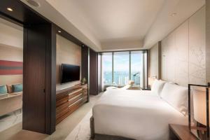 a bedroom with a large white bed and a tv at Conrad Tokyo in Tokyo