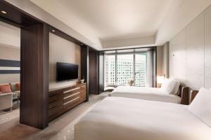 a hotel room with two beds and a flat screen tv at Conrad Tokyo in Tokyo