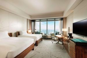 a hotel room with two beds and a flat screen tv at Conrad Tokyo in Tokyo