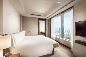 a bedroom with a white bed and a large window at Conrad Tokyo in Tokyo