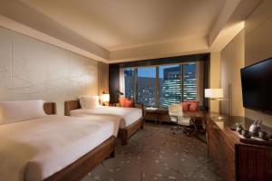 a hotel room with two beds and a large window at Conrad Tokyo in Tokyo