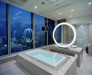 a bathroom with a tub and a round mirror at Conrad Tokyo in Tokyo