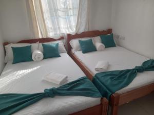 two twin beds in a room with green and white pillows at She-goes apartments in Mombasa