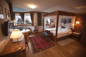 ein Schlafzimmer mit einem Himmelbett und einem TV in der Unterkunft Hotel Garni Concordia - Dolomites Home in Wolkenstein in Gröden