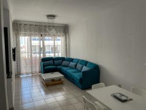 un soggiorno con un divano blu e un tavolo di Apartamento Ajanif Terraza Centro Martil Miramar 100 Metros playa a Martil