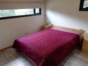 a bedroom with a purple bed with a window at Cabaña Coyam in Villa del Dique