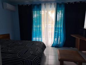a bedroom with blue curtains and a bed and a table at Blue dream Hamaca in Grand-Bourg