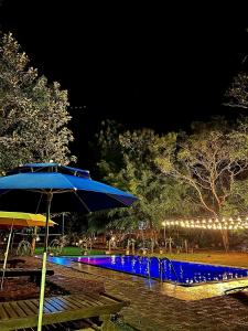 a blue umbrella next to a swimming pool at night at Birds Paradise Inn in Udawalawe