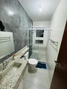 een badkamer met een toilet, een wastafel en een spiegel bij Ap 800m da praia in Rio das Ostras