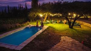 a group of people standing around a swimming pool at night at Miraluna - Cabañas & Bodega in Cachí