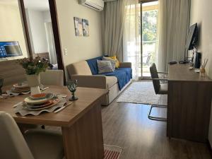 a living room with a table and a living room with a couch at Aconchegante Flat Premiere Rio Centro in Rio de Janeiro