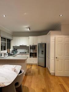 - une cuisine avec des placards blancs, une table et un réfrigérateur dans l'établissement Hunter house, à Camberwell