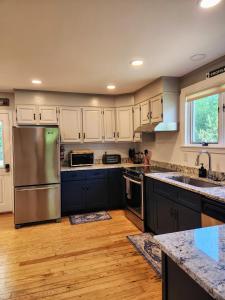 a kitchen with white cabinets and a stainless steel refrigerator at Backyard Bliss in the White Mountains in Lincoln +14 photos
