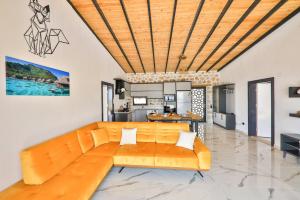 ein orangefarbenes Sofa im Wohnzimmer mit Küche in der Unterkunft Villa kırlangıç in Kaş