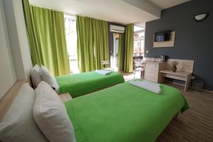 two beds in a room with green curtains at Theatre Apartments in Bitola