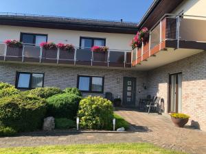 een huis met een balkon met bloemen erop bij Ferienwohnungjahrsfeld in Straßenhaus