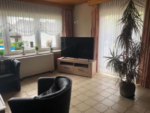 een woonkamer met een televisie en twee stoelen en ramen bij Ferienwohnungjahrsfeld in Straßenhaus