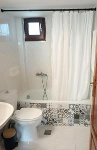 a bathroom with a toilet and a tub and a sink at Holiday home with view in Pefkohori +8 photos