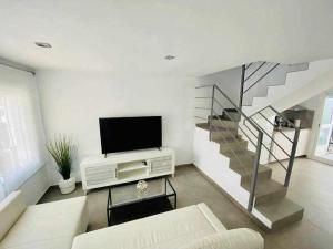 a living room with a television and a staircase at IV Apartamentos Morales & Arnal in Ronda