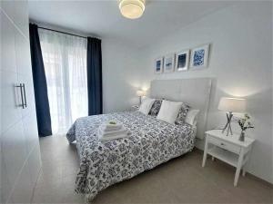 a white bedroom with a bed and a window at XV Apartamentos Morales & Arnal in Estepona