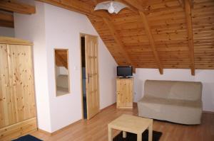 un soggiorno con divano, TV e soffitti in legno di Öregtölgy Panzio a Csongrád