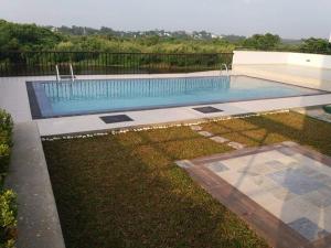 a large swimming pool in a yard with a grassy field at Diyawanna Leisure in Rajagiriya