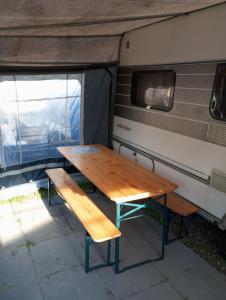 a wooden table and bench in front of a trailer at Domki letniskowe Przyczepy kempingowe Zacisze Mielno in Mielno